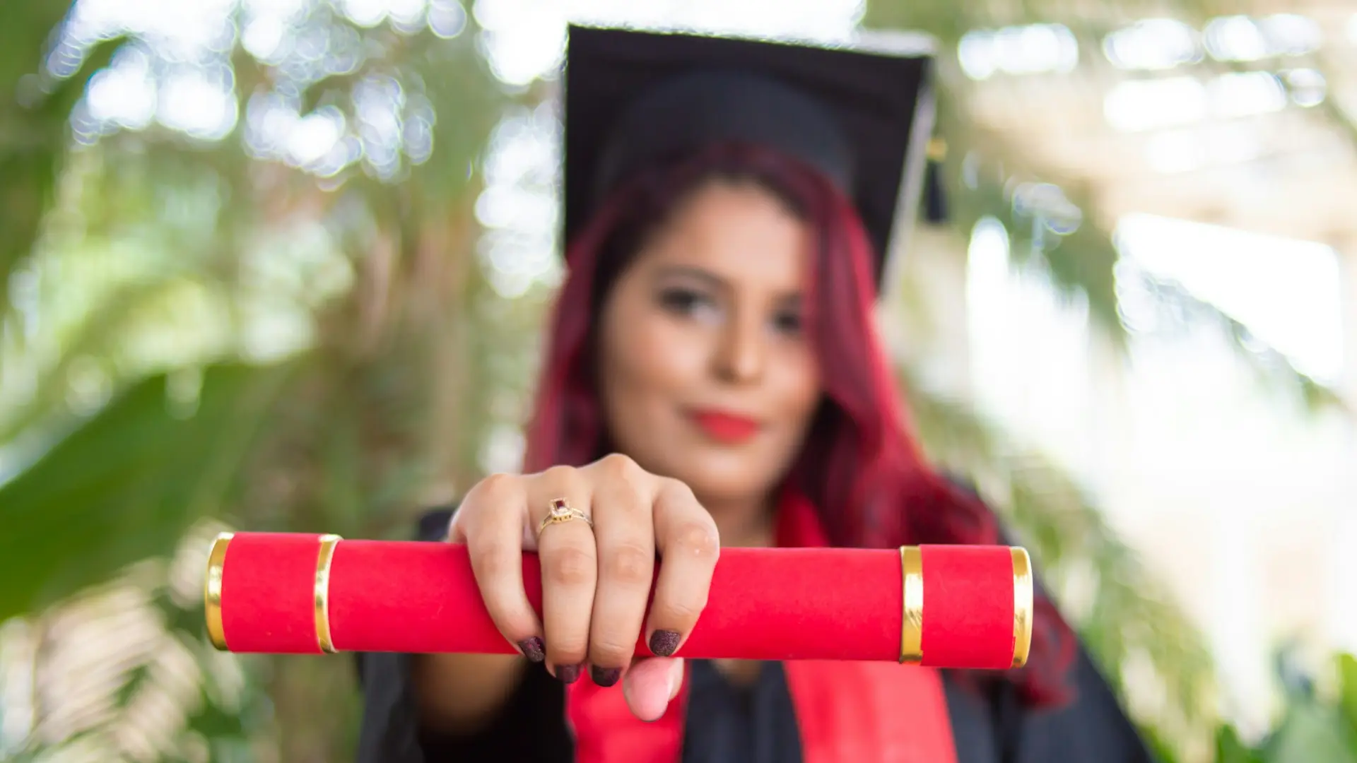 woman in red long sleeve shirt holding red and black academic hat